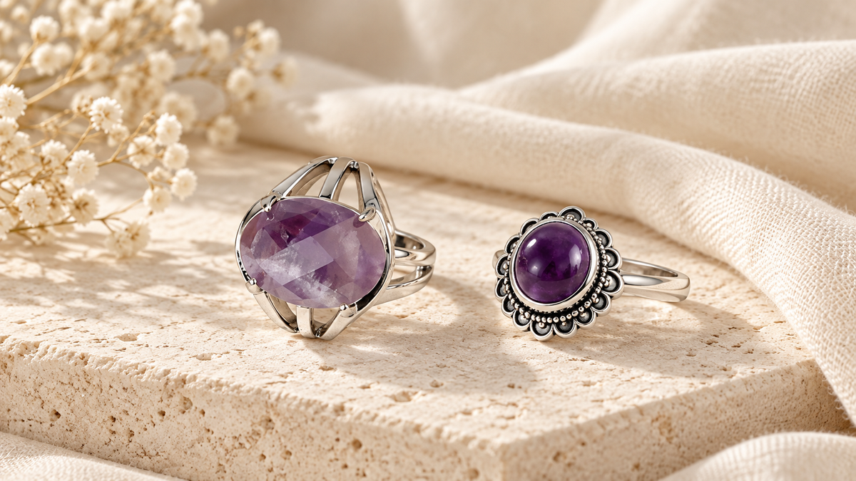 Amethyst-Ring mit glattem Cabochon neben einem Ring mit facettiertem Stein auf hellem Untergrund